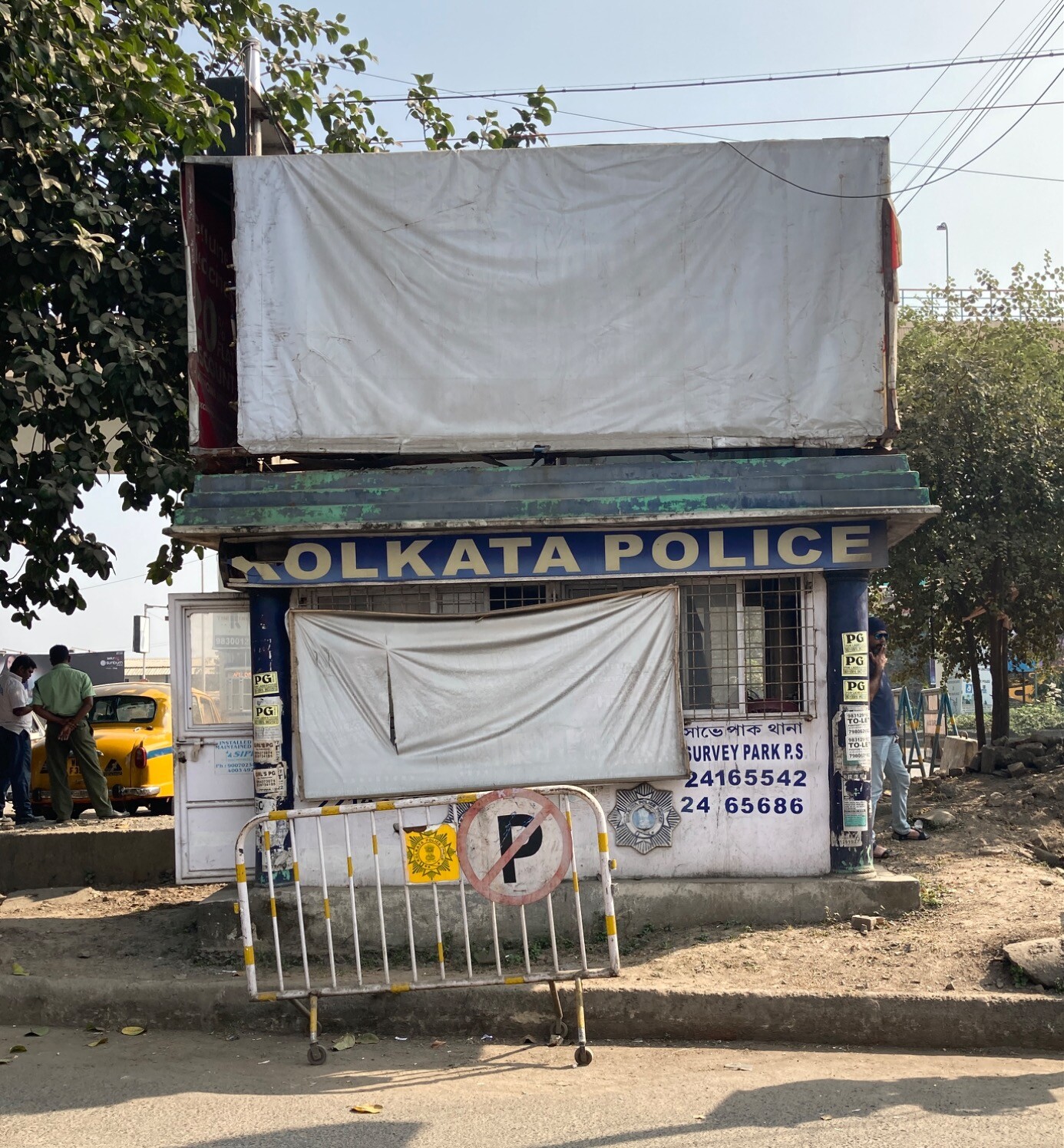 Beside a street, a small kiosk labeled KOLKATA POLICE