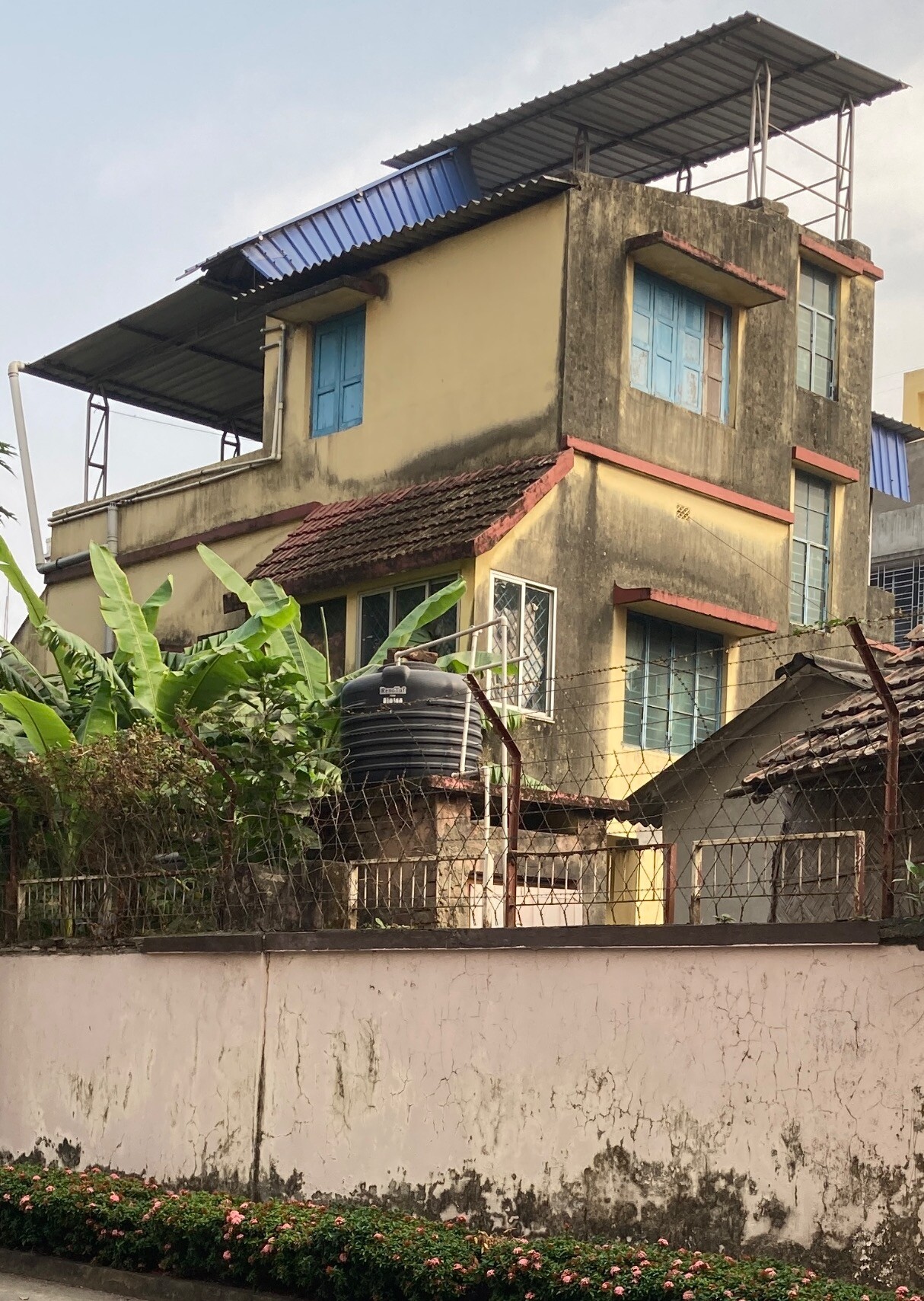 3-storey house whose cream-colored paint has largely gone gray