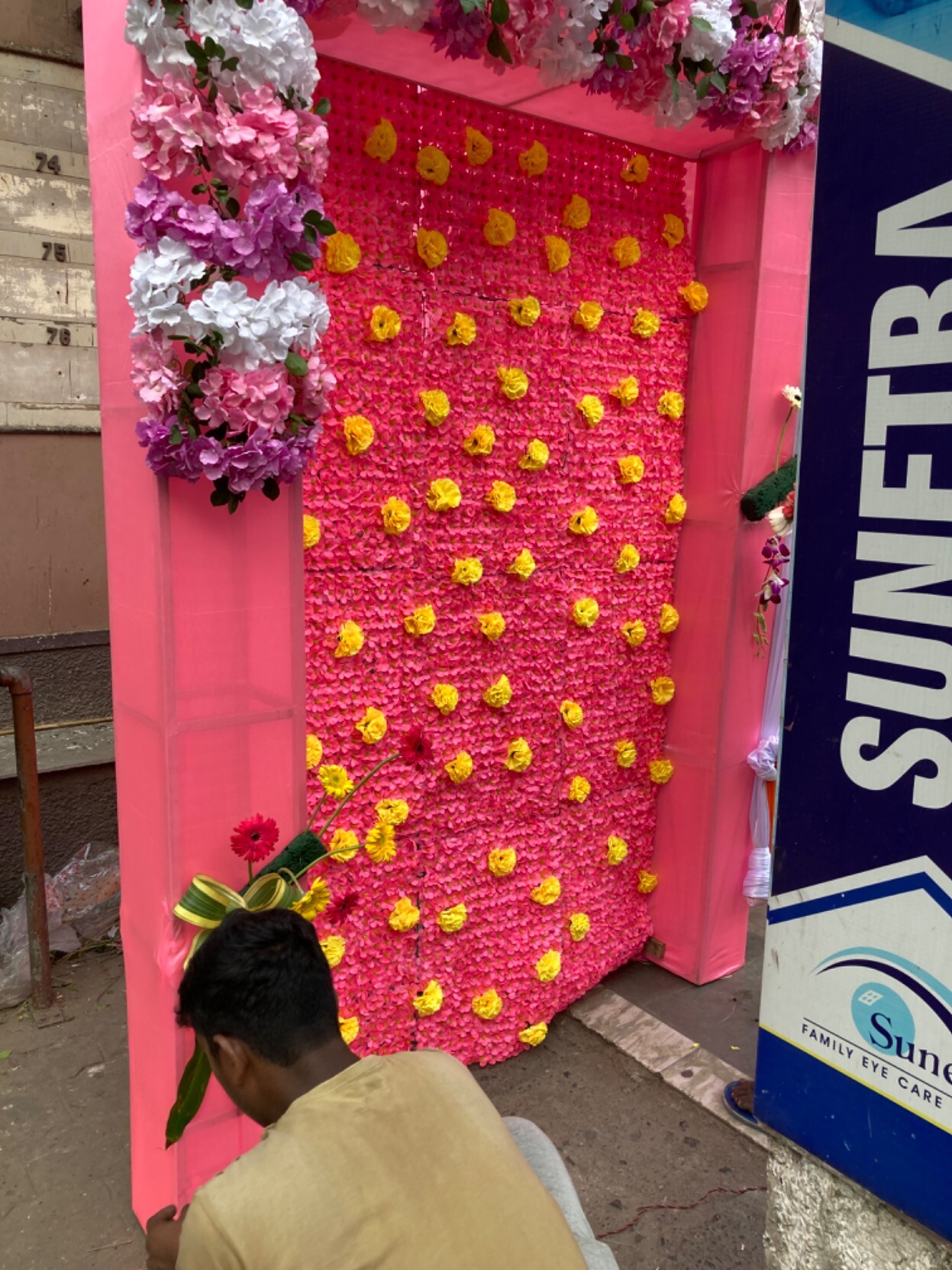 Worker squatting sticking yellow flowers into a red vertical panel