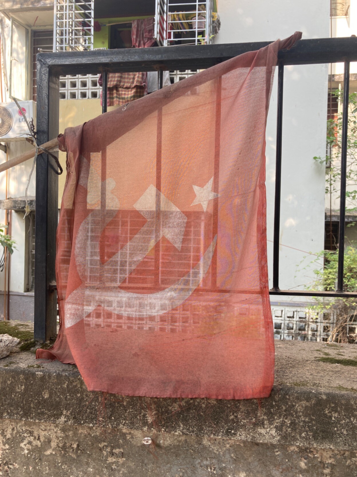 Faded red and white hammer and sickle flag affixed to fence