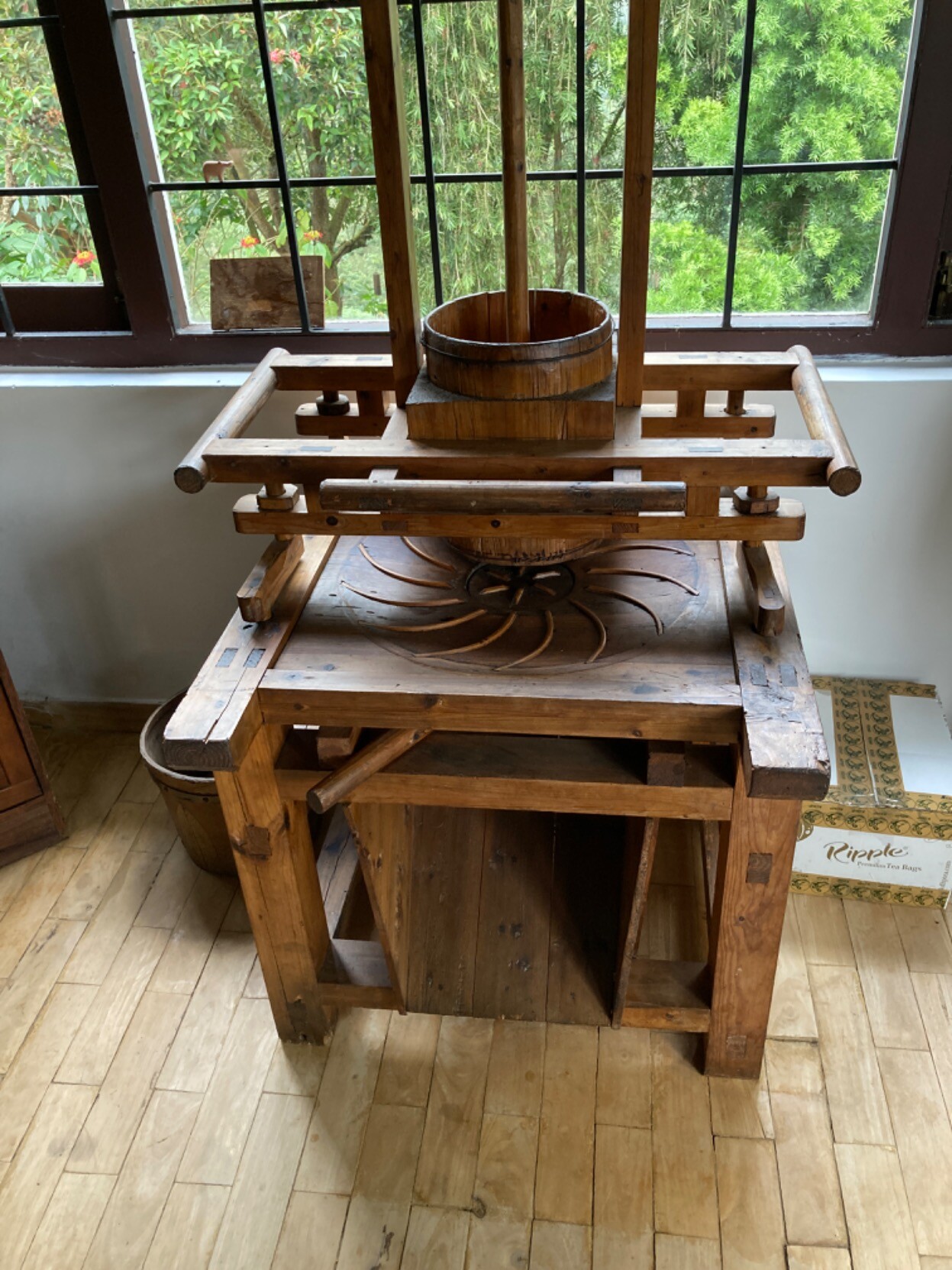 Before a window looking out on trees, pretty much the same kind of machine as in the previous video, except everything is wood and it’s hand-powered