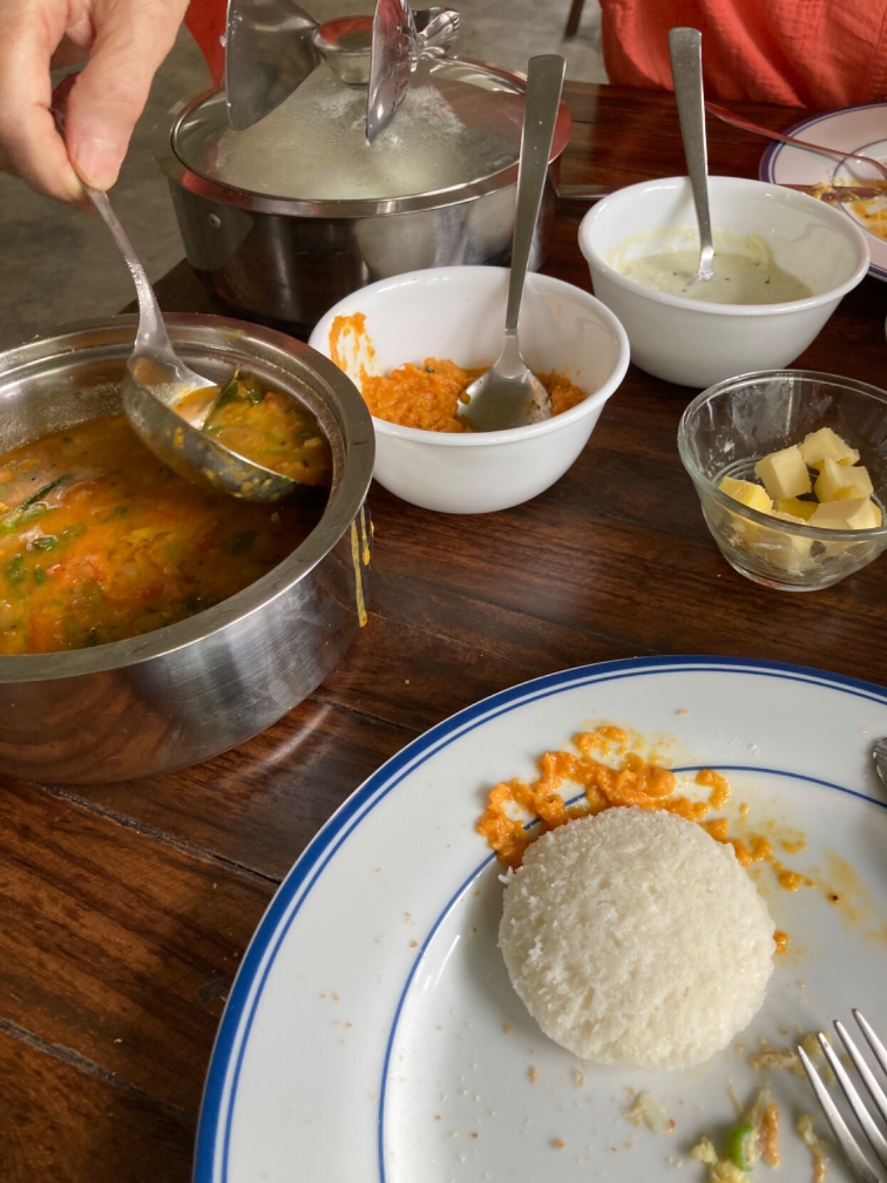 On table, iddli, sambal, tomato chutney, dal, butter, plates