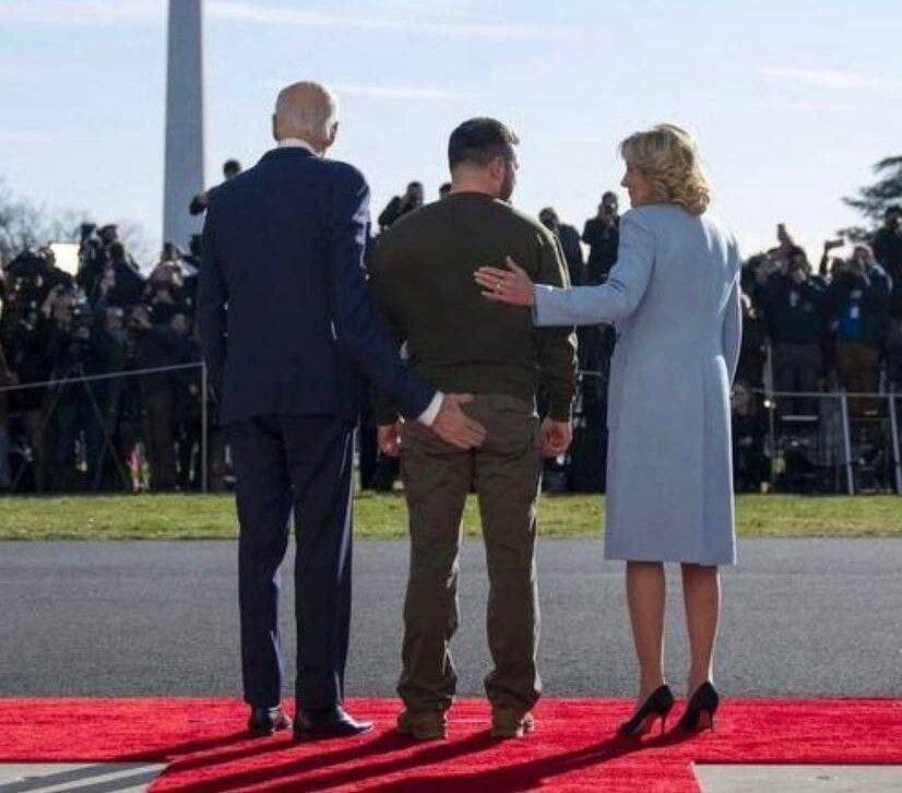 Joe and Jill Biden from the back. Volodymyr Zelenskyy between them. Joe Biden holding his hand at Zelenskyy butt.