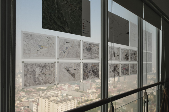 Semi-transparent aerial pictures in front of a large window with the city of Hanoi in the background. These are industrial fabrications sites