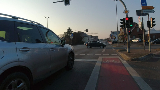 Ein KFZ quert eine Kreuzung, während die Ampel für den Radverkehr bereits grün signalisiert.