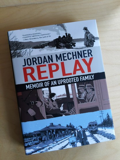 The book "Replay" by Jordan Mechner is lying on a wooden desk.