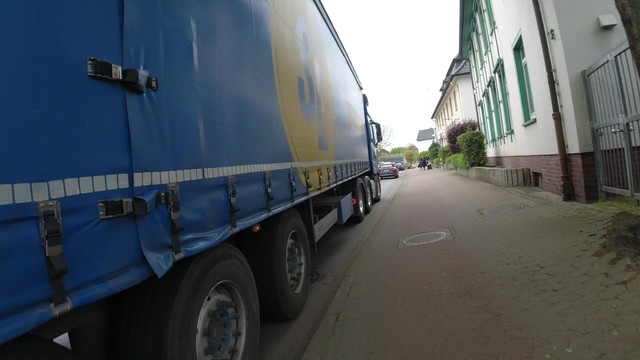 Ein LKW fährt mit Zentimeterabstand auf der Fahrbahn neben einem Hochbordradweg.
