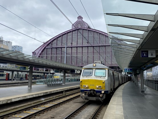 A strange looking Belgian train (an AM75) is waiting outside a train shed (Antwerpen Centraal).