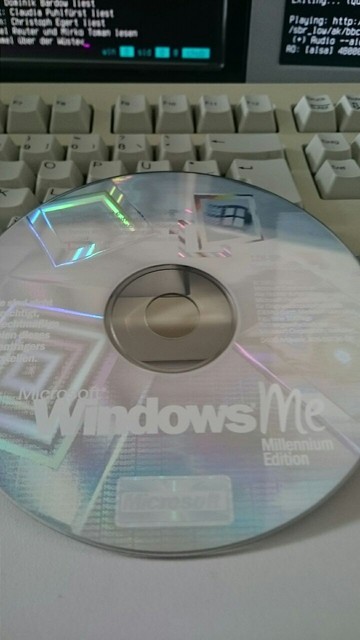 A CD-Rom with text »Microsoft Windows ME Millenium Edition« lying on a computer keyboard. The disc shimmers colorful with counterfeit-proofing elements