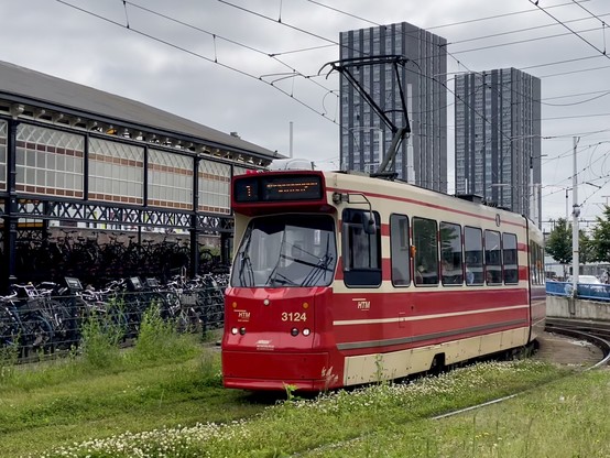 A old-fashioned red and beige tram comes around a corner. It is one of the older trams still in service in Den Haag. 