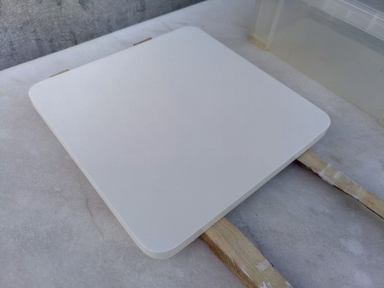 The seat of the stool, now painted entirely in plain white. It's resting on two scrap sticks.