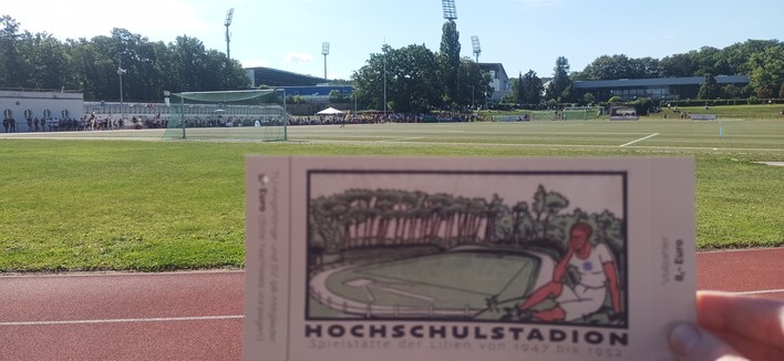 Originelle Eintrittskarte mit Aufdruck Spielstätte der Lilien von 1947 bis 1952.
Dahinter Flutlichter und Tribünen des Stadion am Böllenfalltor.