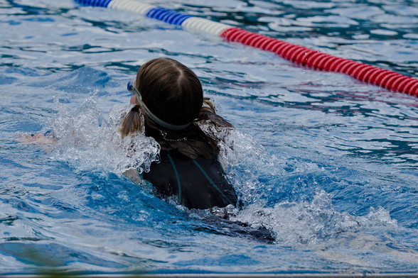 Schwimmerin von hinten im Schwimmbad mit spritzender Bugwelle