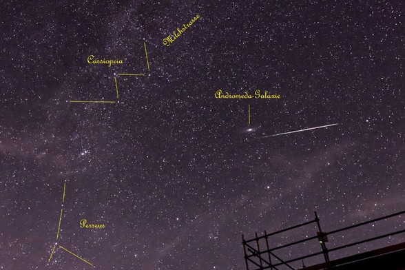 Sternhimmel am 11.08.2024 gegen 23:30 in Richtung Osten, links oben Sternbild Cassiopeia (das Himmels-W), links unten das Sternbild Perseus, aus dem heraus die August-Sternschnuppen zu kommen scheinen. Nahe der Bildmitte ein heller Fleck - die Andromeda-Galaxie. Knapp darunter eine helle Leuchtspur - ein Perseide (Sternschnuppe). Unten am Bildrand die Silhouette des Baugerüstes von Haus 5 der Sternwarte Sonneberg. Außerdem ganz viele Sterne über das Foto verteilt und schwach zu sehen das Band der Milchstraße, welches durch Cassiopeia geht.