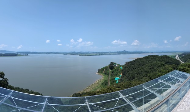 A photo shot from the Odusan Unification Observatory showing the river separating the two Koreas and a hilly rural landscape on the North Korean side of the river.