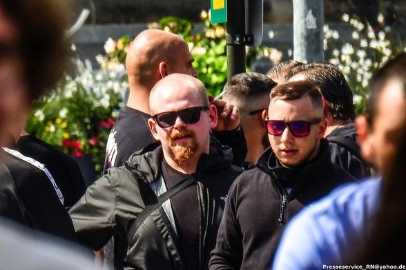 Max Sieler blickt mit Glatze, Sonnenbrille, rot-blondem Vollbart und Northface-Jacke in die Kamera.