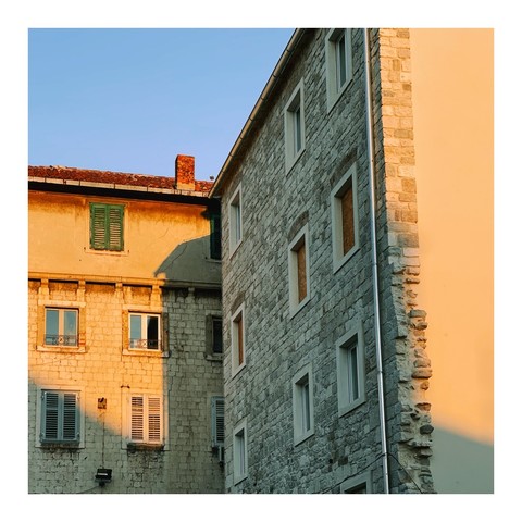 Gelbe Hausfassade über Eck in Abendlicht und ein Stück blauer Himmel 