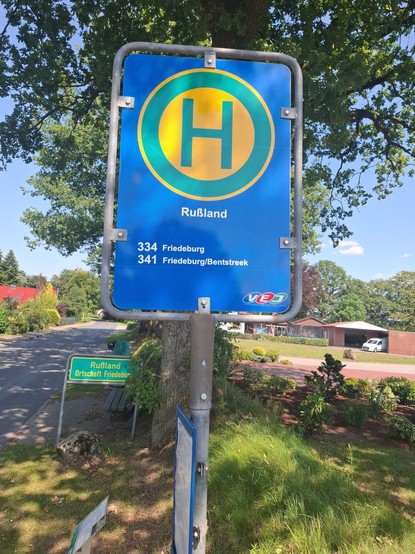 Haltestellenschild mit Buslinien nach Friedeburg. Im Hintergrund Ortsteilschild mit 