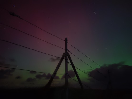 Rot-grünlich schimmernder Himmel, verdeckt von ein paar wenigen, kleinen Wolken.
unter dem Horizont ist fast schwarzer Boden. Vor der Szene ist ein Draht-Zaun mittig mit Pfeiler, der Teile der Szenerie verdeckt.