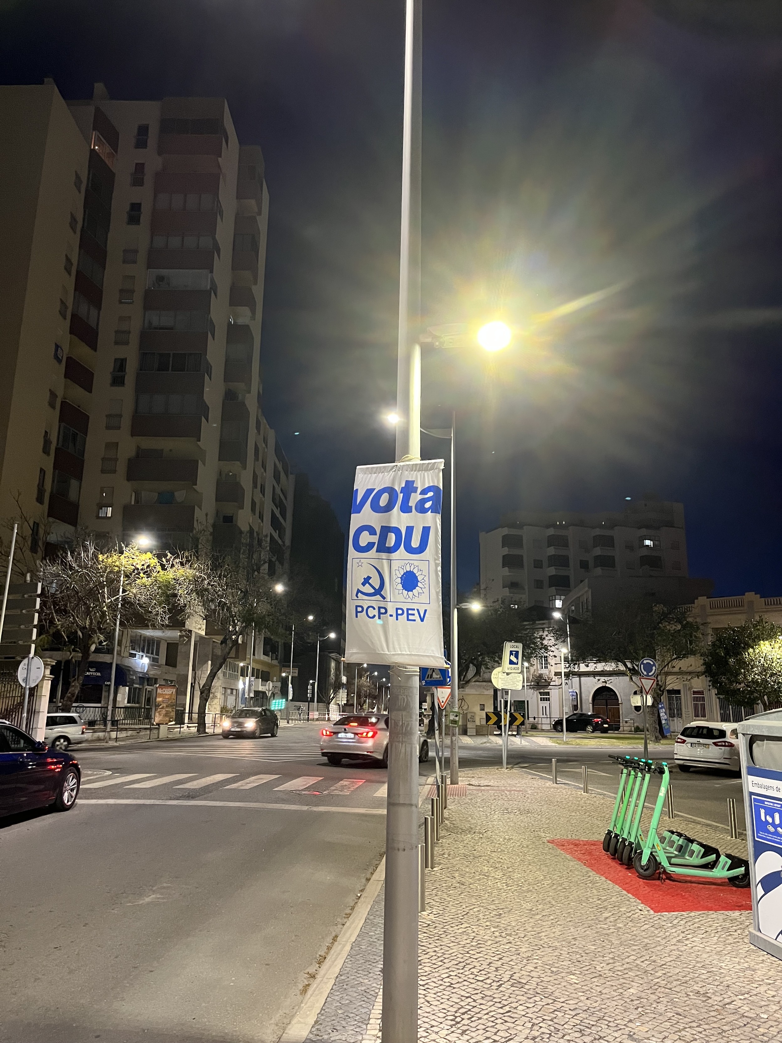 Ein Plakat zu den portugiesischen Parlamentswahlen mit dem Schriftzug „Vota CDU - PCP-PEV“ dazu sind das Logo der PCP (Hammer und Sichel) sowie der PEV (grüne - stilisierte Sonnenblume) zu sehen.
Es ist ein einfaches Plakat an einem Laternenmast. Ein Plakat zu den portugiesischen Parlamentswahlen mit dem Schriftzug „Vota CDU - PCP-PEV“ dazu sind das Logo der PCP (Hammer und Sichel) sowie der PEV (grüne - stilisierte Sonnenblume) zu sehen.
Es ist ein einfaches Plakat an einem Laternenmast.