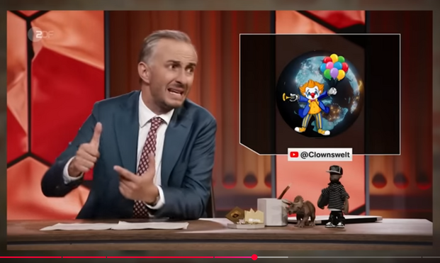 Screenshot aus dem verlinkten Youtube-Video.

Links Jan Böhmermann, rechts ein Comic-Clown mit bunten Lufballons.