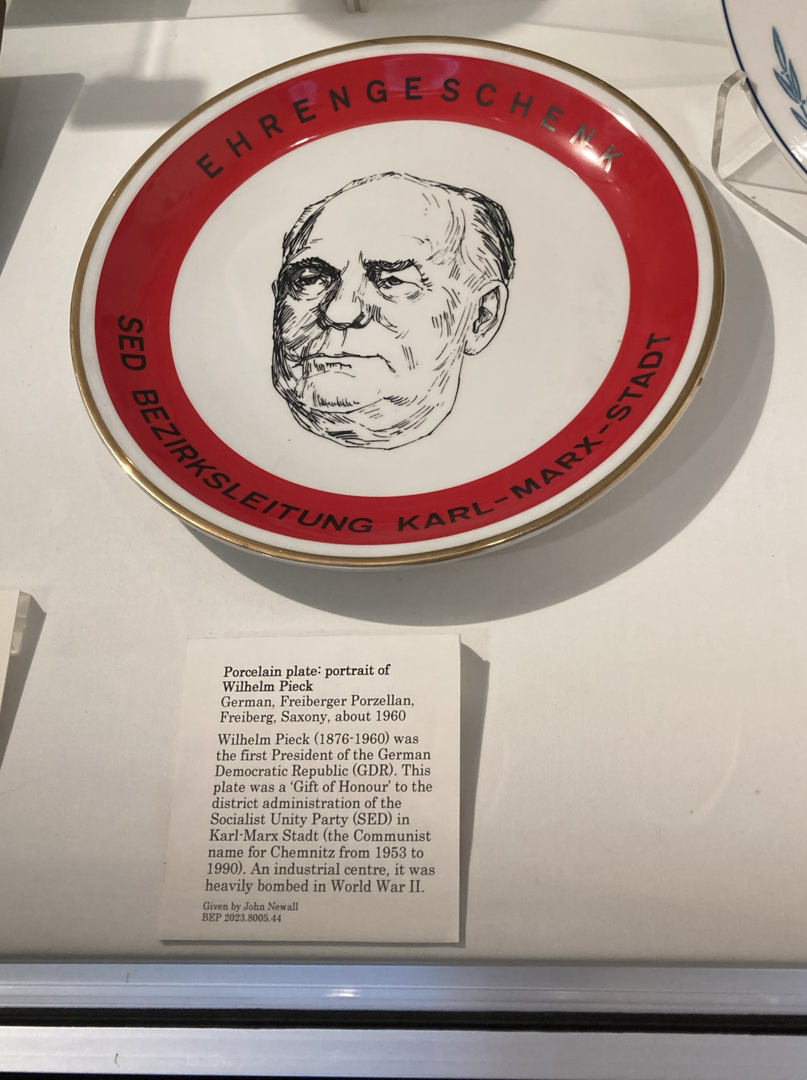Pen and ink sketch of the old guy’s face at the center. Caption: Wilhelm Pieck (1876-1960) was the first President of the German Democratic Republic (GDR). This plate was a