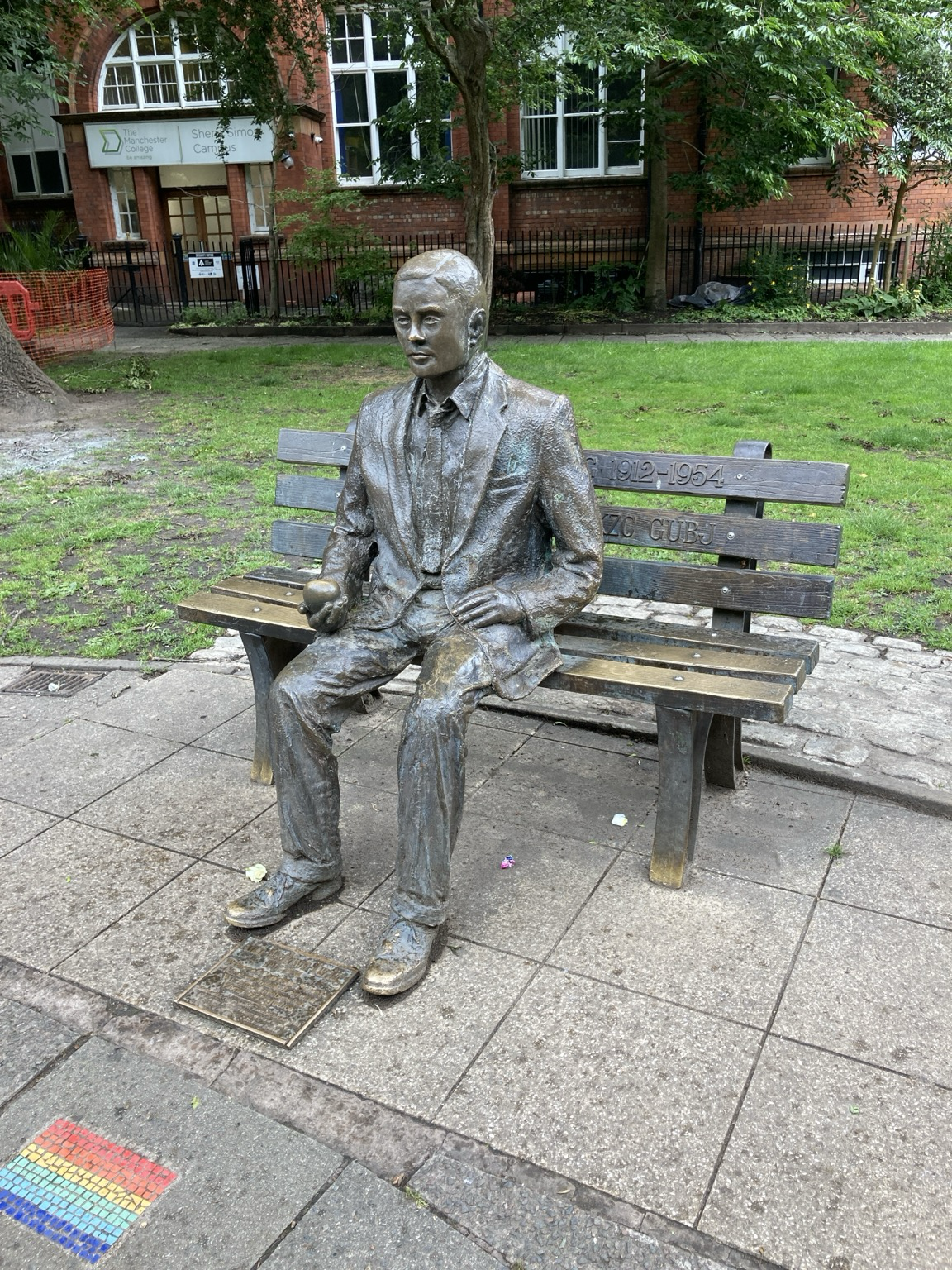 Bronze of Turing sitting on a park bench holding an apple