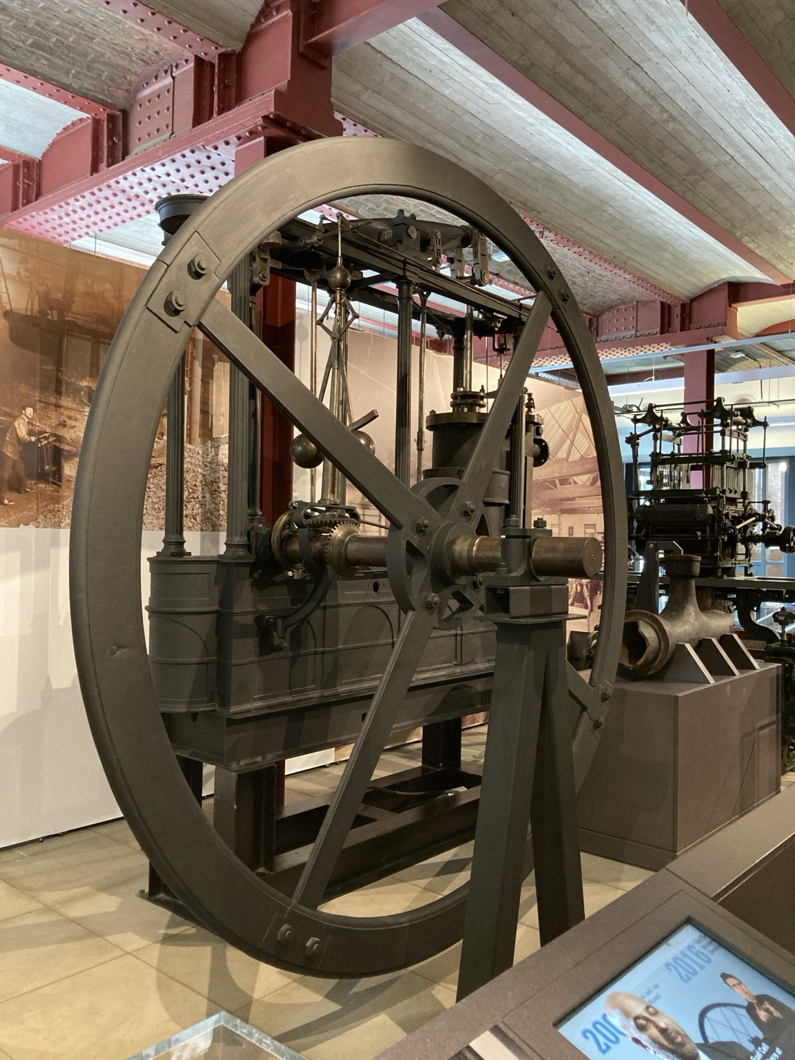 A giant iron wheel and a maze of iron plumbing embedded in a frame made of iron and wood