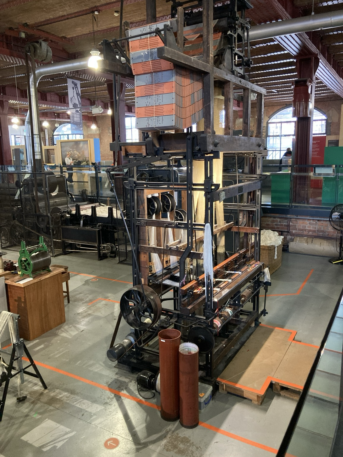 Inside a talk iron and wood frame, rollers and countless threads and an accordioning deck if punch cards