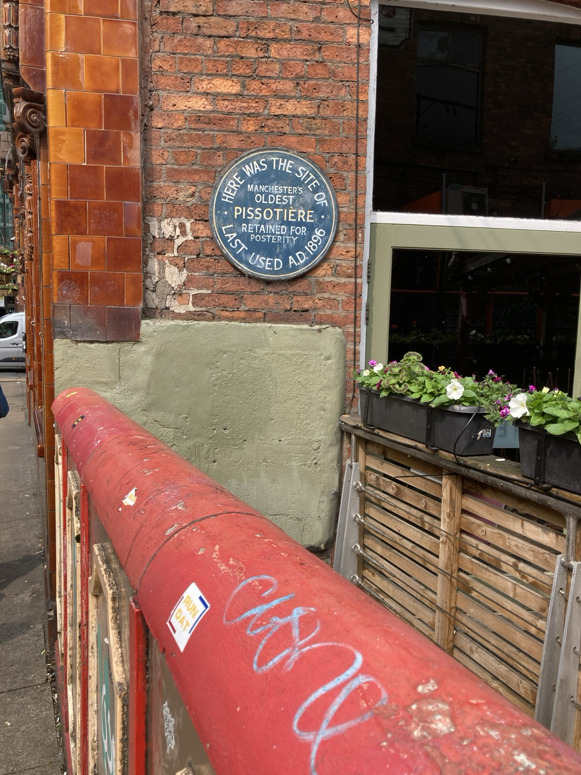 Plaque: HERE WAS THE SITE OF MANCHESTER’S OLDEST PISSOTIÈRE RETAINED FIR POSTERITY LAST USED AD 1895