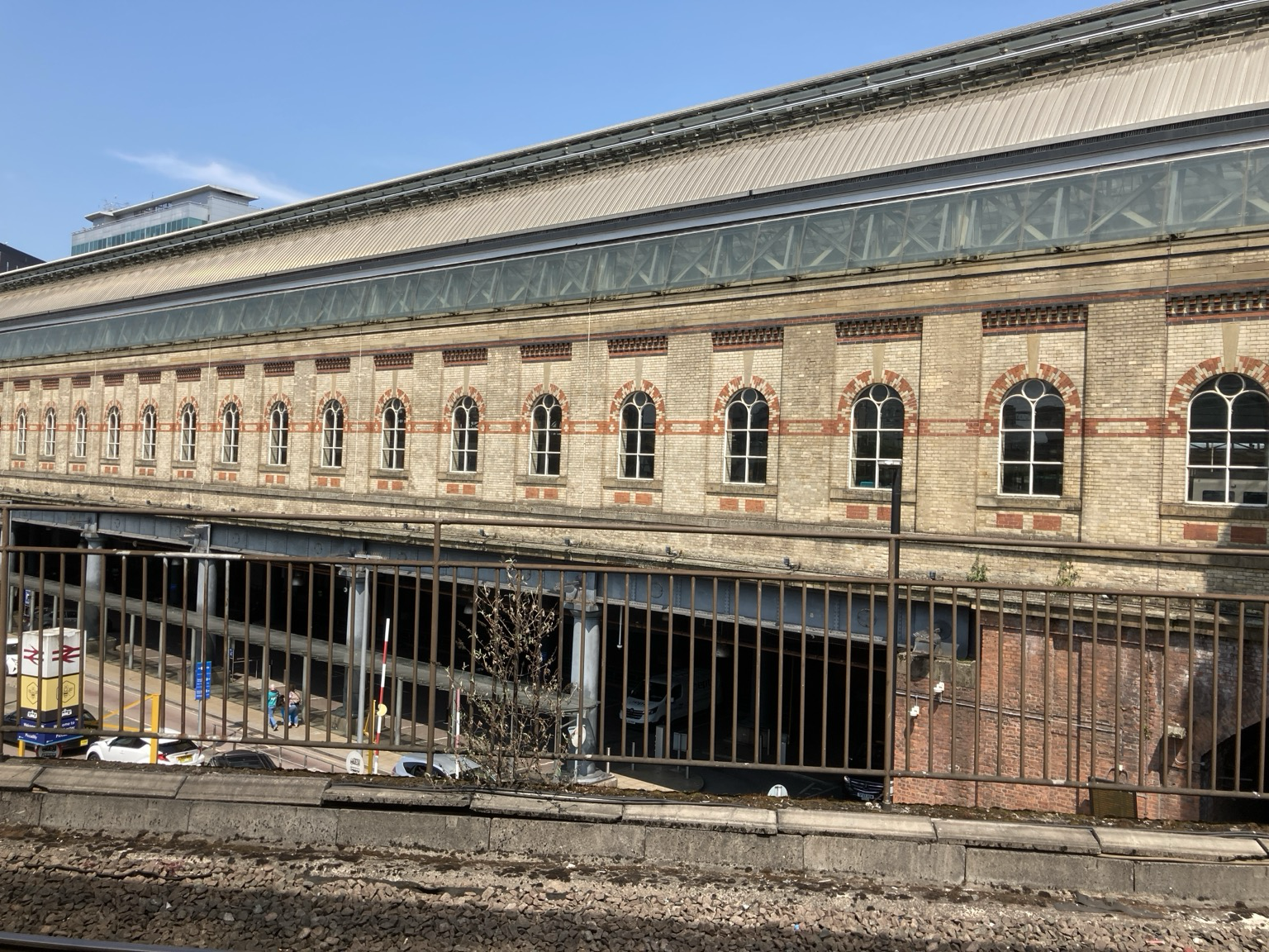 From behind a railing, the view toward a long masonry building with arched windows