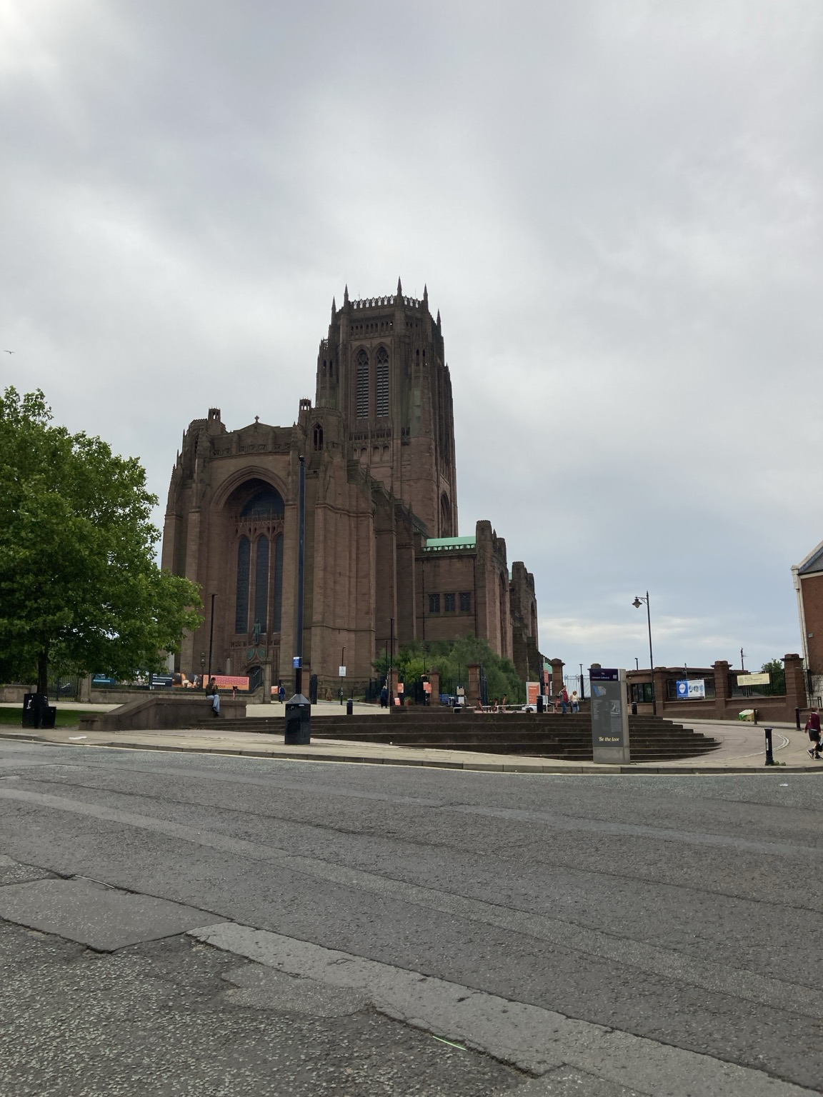 From across the street, tall brown stone church with tower surmounted by spikes