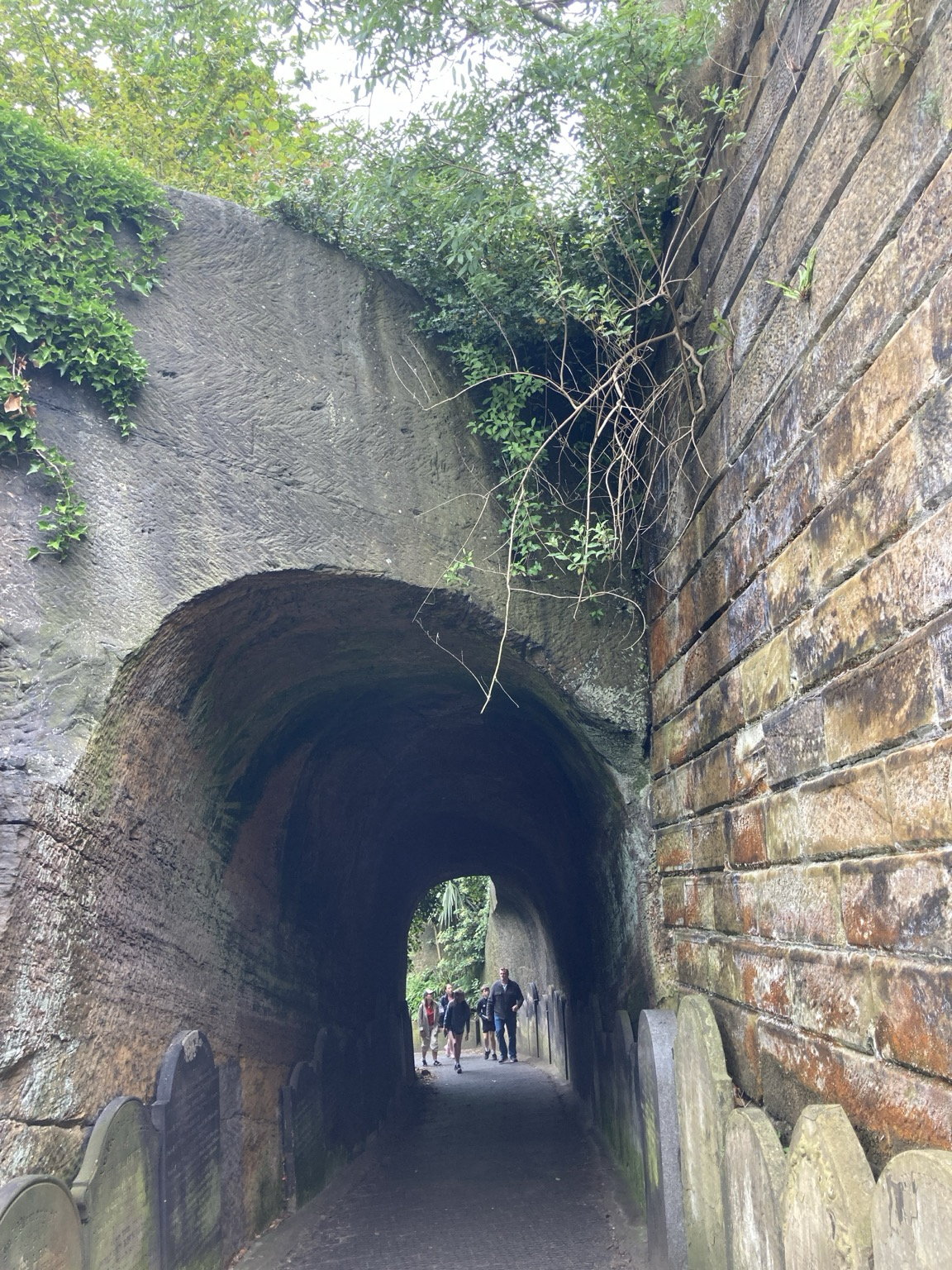 Looking into an arched stone tunnel with people in the gloom