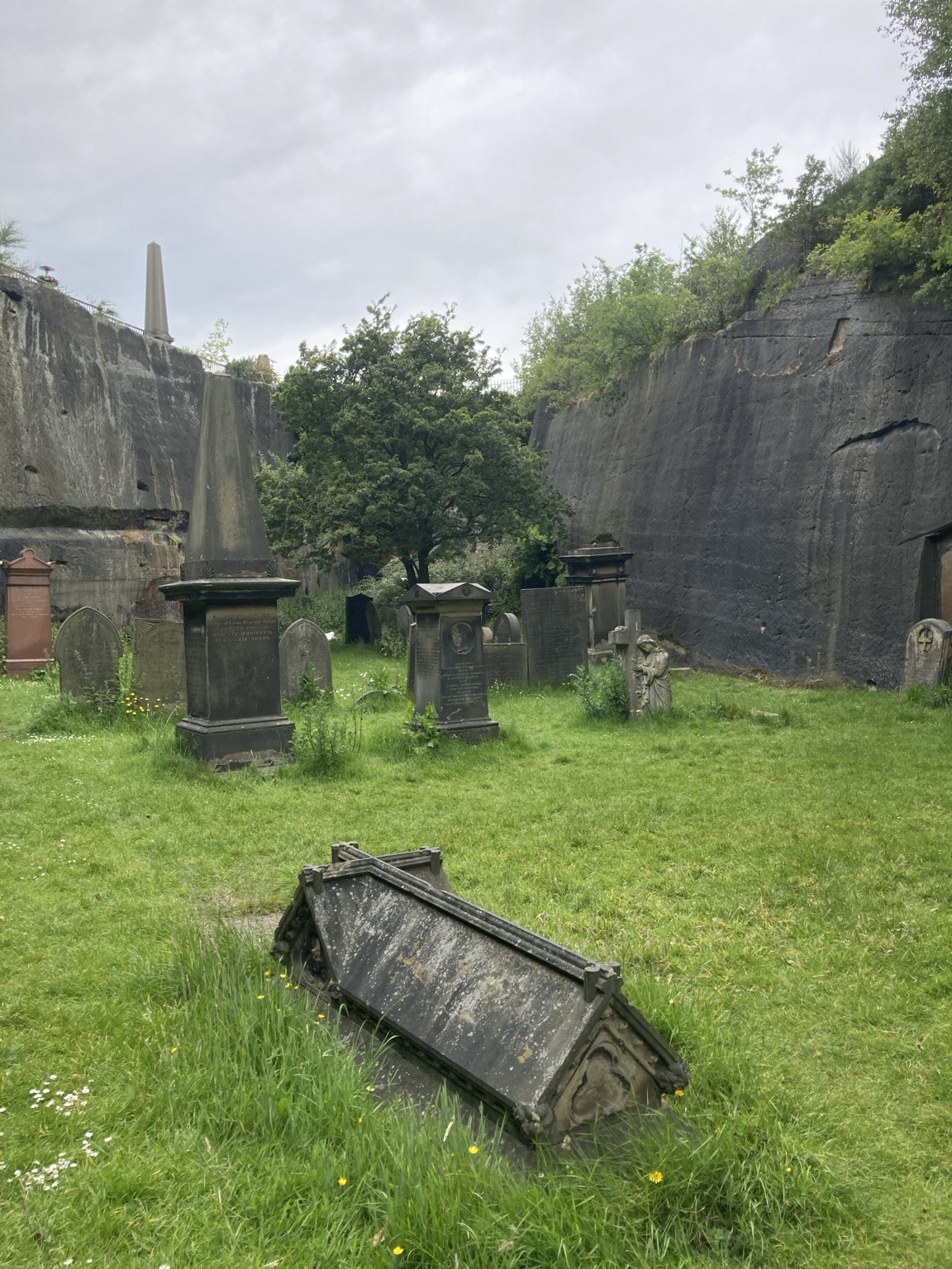 Enclosed by rock walks maybe 15m high, green lawn with scattered stone tombs