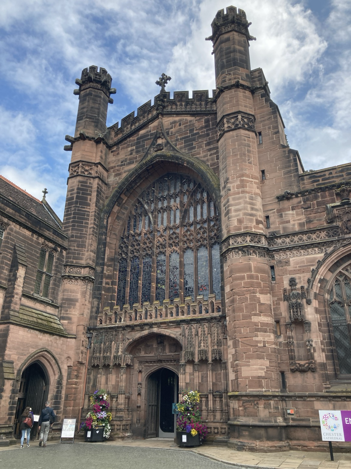 Main entrance of soot-stained sandstone with towers and a multistory arched window.