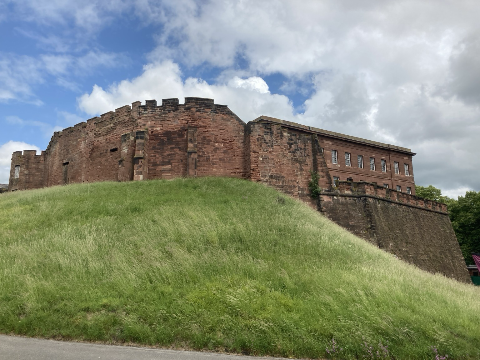 Red sandstone castle with crenellated battlements on a green bluff