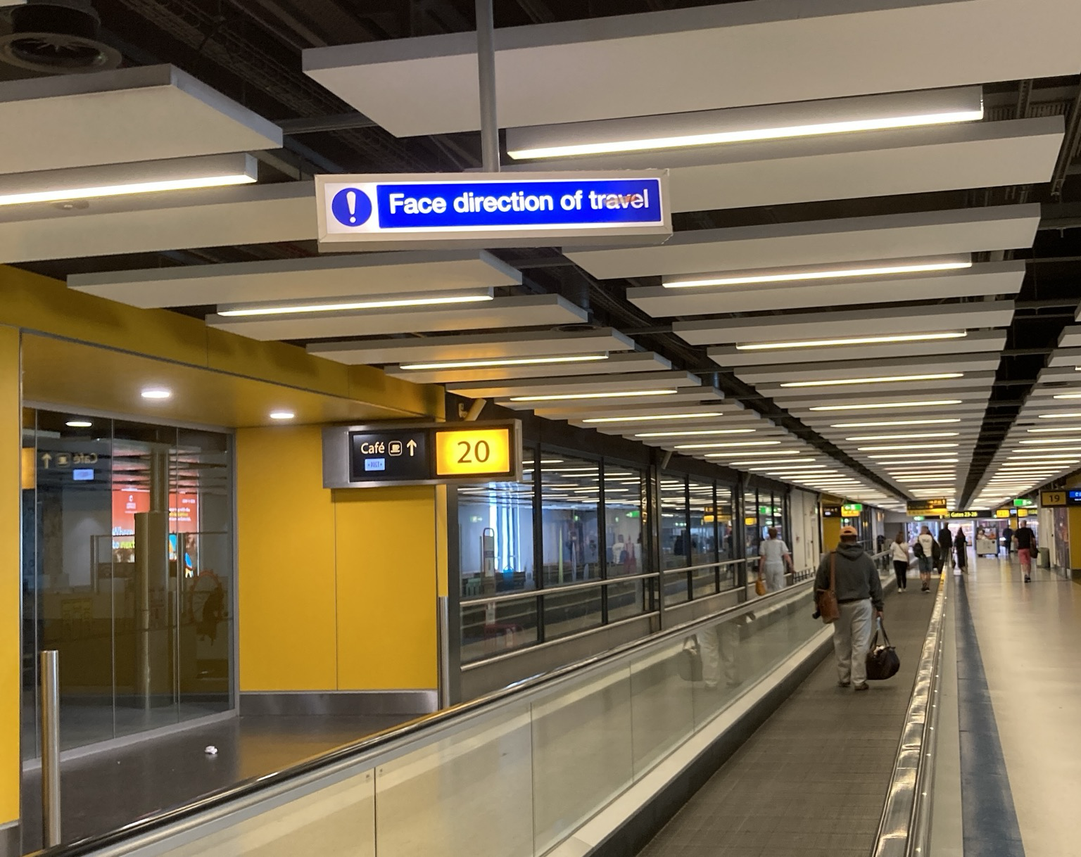 Over a moving sidewalk, a warning sign: Face direction of travel