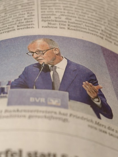 Neuer MMT-Lehrbuchbeitrag incoming. Kanzler Merz vor einem Rednerpult, suggerierend, dass er ja leider trotz allem nichts tun könnte