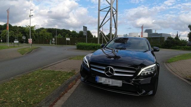 Ein dunkler Mercedes möchte aus der verkehrten Richtung kommend auf die falsche Spur aus einem Kreisel ausfahren und steht mit seiner Front im Gegenverkehr.
