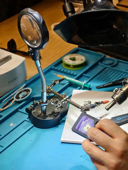 Using a bunch of tools to open a little plastic token that functions as a tape for a "Galakto" audio box. These magnetically attach on top of these little boxes. Very easy to use. This is the setting of a makerspace with iFixit tools and more. Colorful
