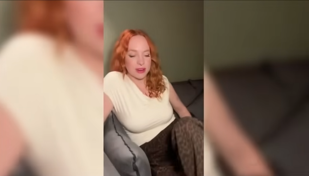 Screenshot aus einem KI-generierten youtube Werbespot: Eine junge Frau mit langen roten lockigen Haaren sitzt auf einem Sofa.
Im Video spricht sie darüber, dass ihr Stiefsohn einen "speziellen Trick" angewendet hat und berichtet über sich daraus ergebende sexuelle Erfahrungen.