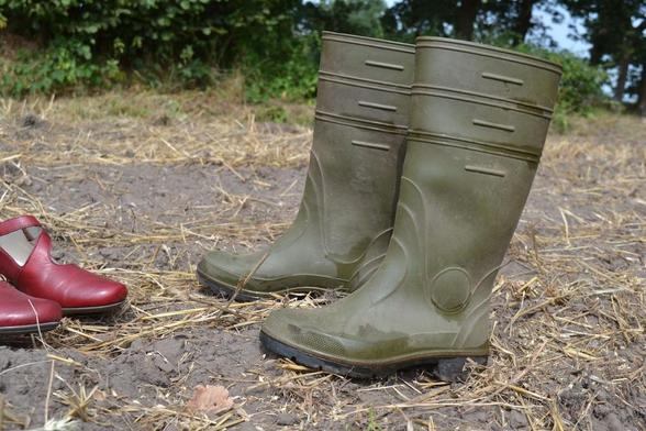 Das Foto zeigt ein Paar benutzte aber gereinigte Gummistiefel, die auf der Erde stehen.
