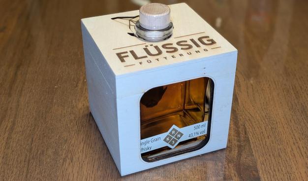 Ein sehr junger Whisky aus lokaler Produktion in einer fast würfelförmigen Halbliterflasche, welche in einem würfelförmigen Holzkistchen verpackt ist. Die Aufschrift lautet Flüssigfütterung.