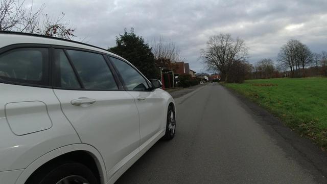 Ein weißes KFZ überholt einen Radfahrenden mit deutlich zu wenig Abstand. Das Bild ist aus der Lenkerperspektive aufgenommen.