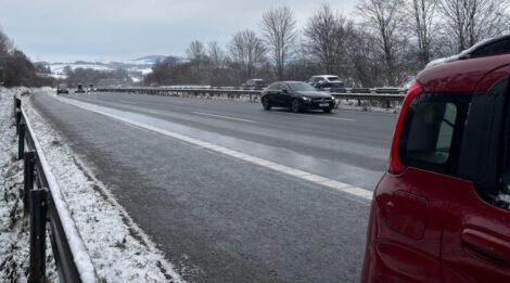 Rechts im Bild sieht man das heck der beifahrerseite eines Fiat Panda auf dem Standstreifen einer Autobahn. Der Blick geht nach hinten und man sieht die zweispurige Autobahn. Im Hintergrund ist in weiter Ferne eine Hügelkette zu sehen.