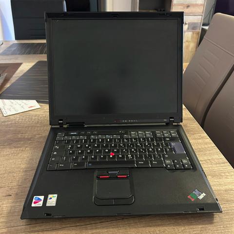 Ein geöffnetes, schwarzes IBM ThinkPad R52 Notebook steht auf einem Holztisch. Der Bildschirm ist schwarz.