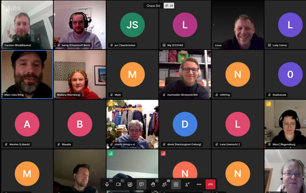 Screenshot der Jitsi-Video-Konferenz: 24 kleine User-Bilder. Circa die Hälfte hat die Kamera an, der Rest wird durch bunte Kreise mit den Anfangsbuchstaben des Namens symbolisiert.