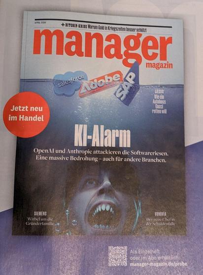 Titelbild der April-Ausgabe des Manager-Magazins als Werbeanzeige im Spiegel. Der Titel lautet: „KI-Alarm: OpenAI und Anthropic attackieren die Softwareriesen. Eine massive Bedrohung – auch für andere Branchen.“ Abgebildet sind die Firmenlogos von Salesforce, Adobe und SAP, die an der Meeresoberfläche dümpeln. Auf das Filmplakat des Weißen Hais anspielend, lauert ein leicht entmenschlichter Sam Altman mit Haizähnen in der Tiefe und blickt angriffslustig nach oben.