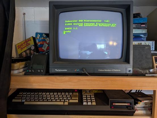 Ein Amstrad CPC 664 steht in einem Regal und zeigt den Startbildschirm.