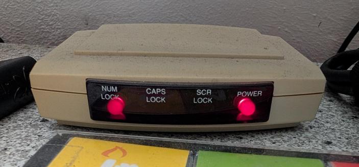 Der beige aEmpfänger einer alten Infrarot-Tastatur mit LED für "NumLock", "CapsLock", "ScrLock" und "Power".
